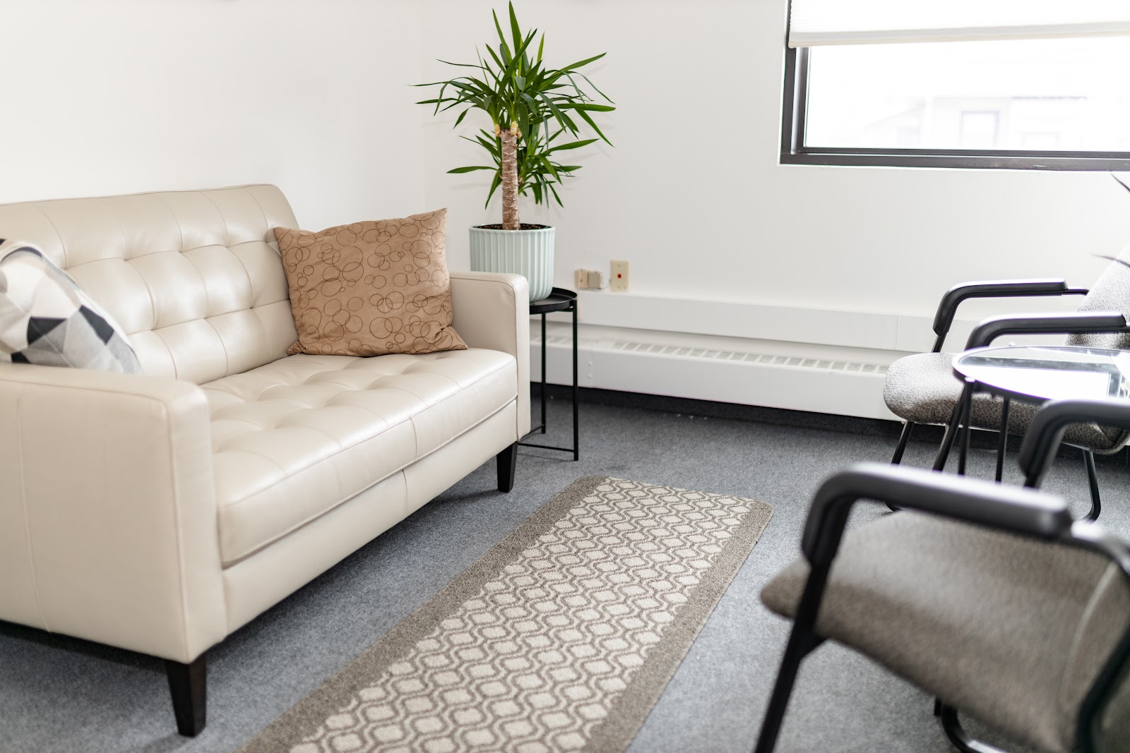 Interior consultation space with cream sofa, potted plant, side table, and professional seating arrangement