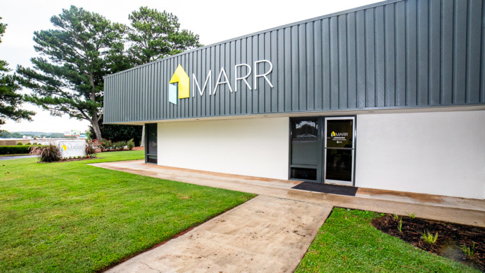 Exterior of contemporary metal-frame facility building with MARR logo signage, landscaped grounds, and glass entrance doors