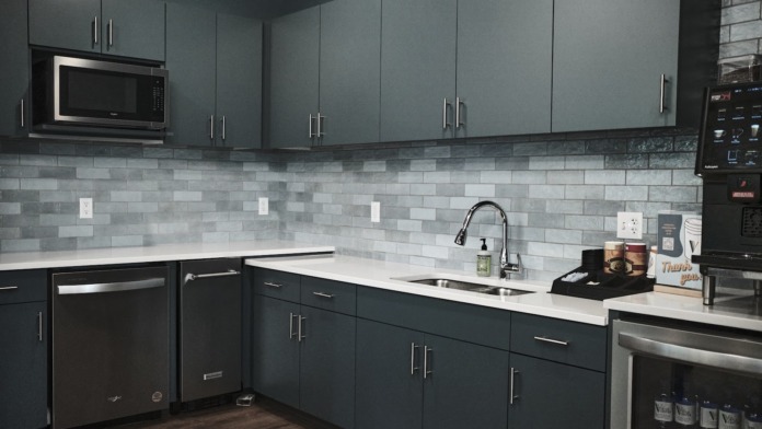 Interior kitchen space with gray cabinetry, tile backsplash, stainless steel appliances, and white countertops