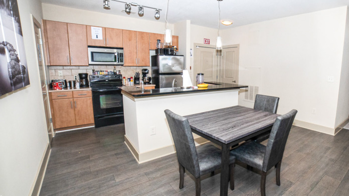 Interior kitchen with wood cabinetry, stainless steel appliances, and dining table with seating for community meals
