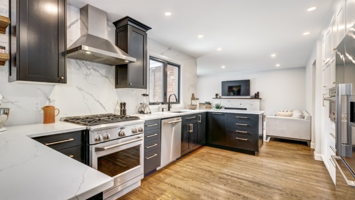 Interior kitchen featuring dark cabinets, marble backsplash, stainless steel appliances, and island seating