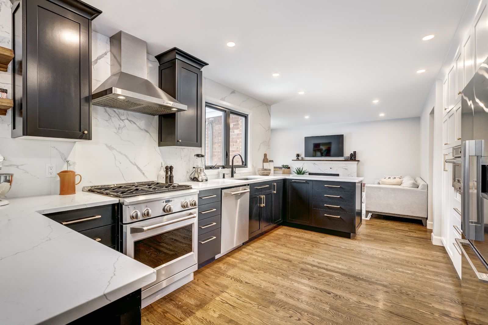 Interior kitchen featuring dark cabinets, marble backsplash, stainless steel appliances, and island seating