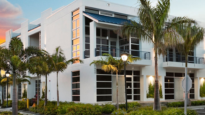 Exterior front facade of white modern treatment facility with palm trees and contemporary architecture at golden hour sunset