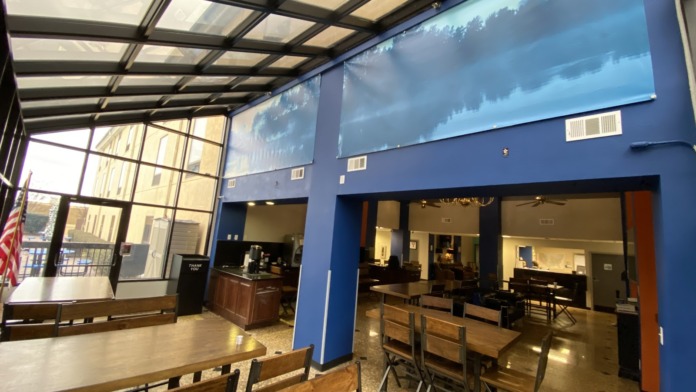Interior space with blue walls, wooden tables, chairs, windows with scenic views, and open layout