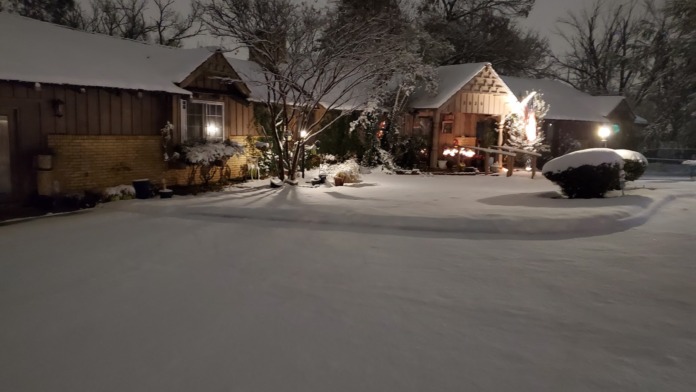 Nighttime exterior showing multiple illuminated residential buildings with snow and landscaping