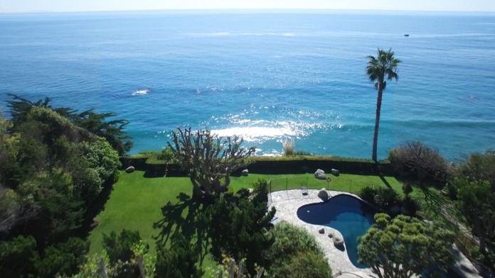 Exterior aerial view of treatment facility cliffside property with swimming pool, manicured lawns, and ocean views