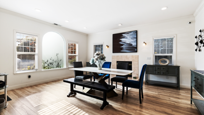 Interior office space with dining table, office chairs, multiple windows with shutters, desk areas, hardwood flooring