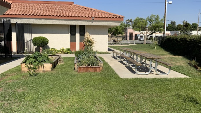 Exterior grounds with building, planted areas, picnic table, grass lawn, and facility signage visible