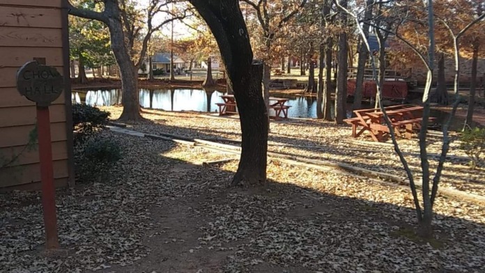 Exterior grounds showing grassy area with picnic tables, cornhole game, and facility building in background