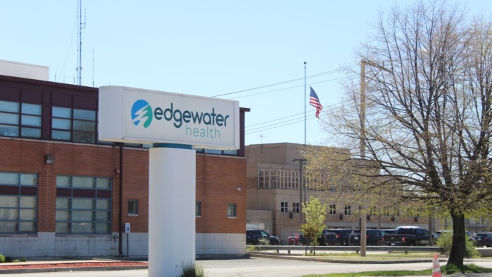 Exterior view showing Edgewater Health facility parking lot with directional signage, trees, and surrounding urban streetscape