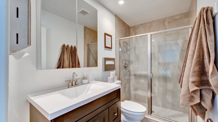 Interior bathroom with vanity sink, mirror, walk-in shower with glass doors, and neutral tile and decor throughout