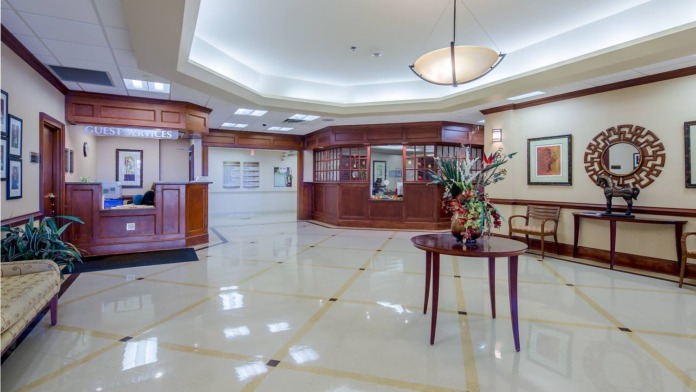 Interior hallway with windows, plant decor, and doors leading to patient rooms with soft natural lighting