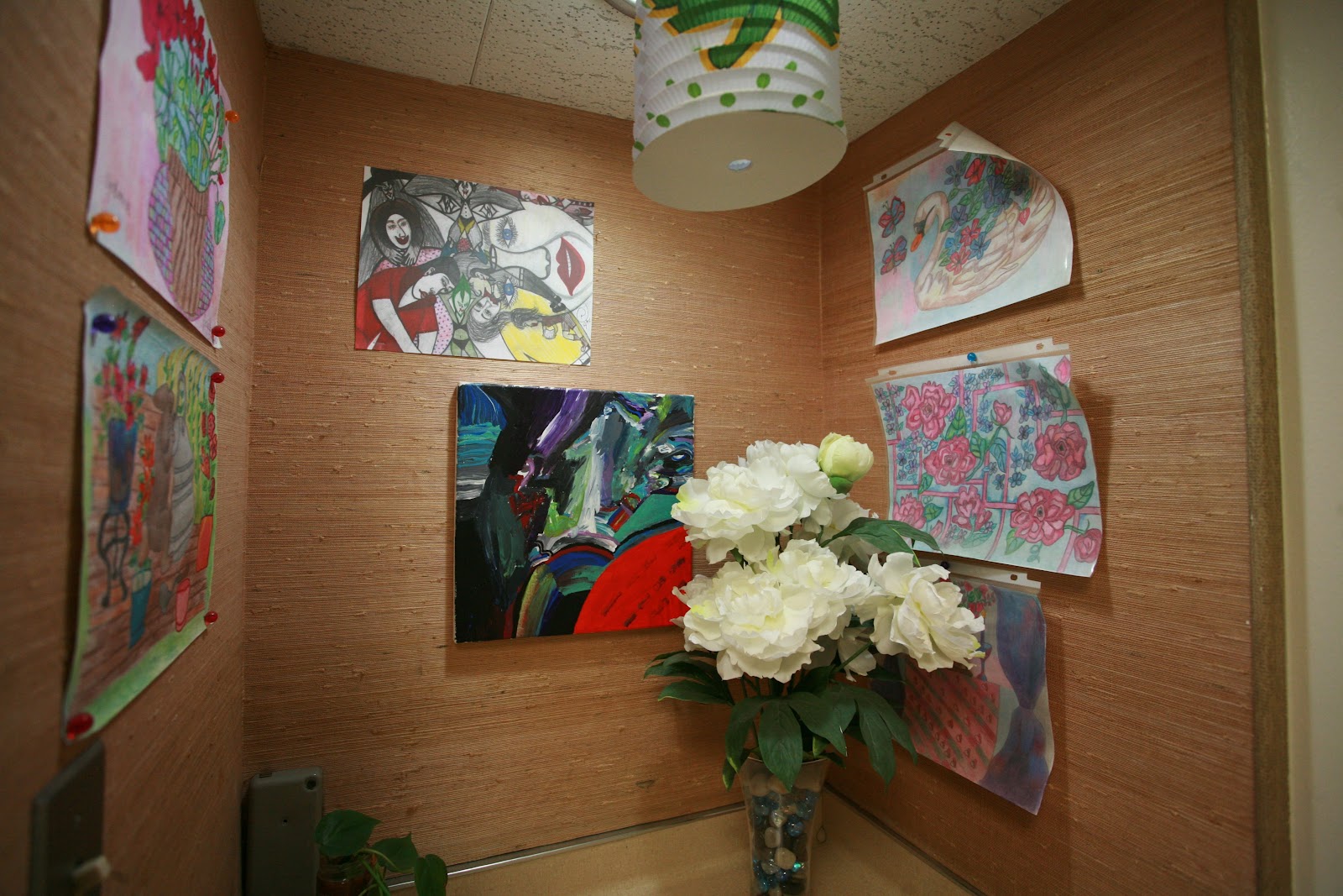 Interior hallway with wood-textured walls, multiple patient room doors, artwork displays, and decorative vase