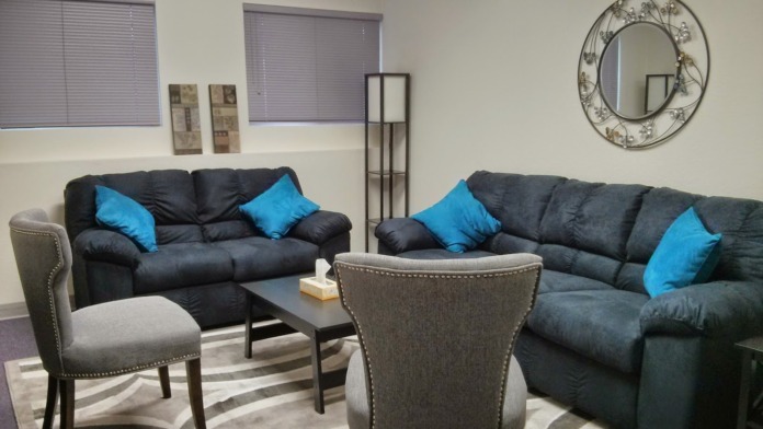 Interior lounge space with two black sofas, blue accent pillows, small table, and patterned area rug.