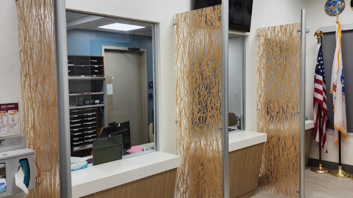 Interior reception desk with decorative carved wood partitions, windows, American flags, ceiling lights, and professional clinic check-in workspace