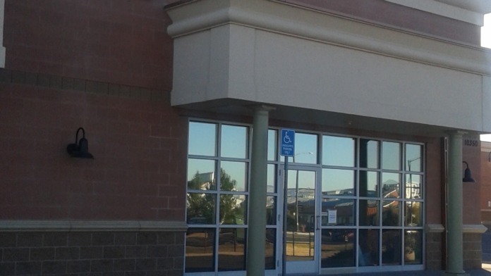Exterior entrance showing All Health Network signage, glass doors, brick walls, and accessible parking sign