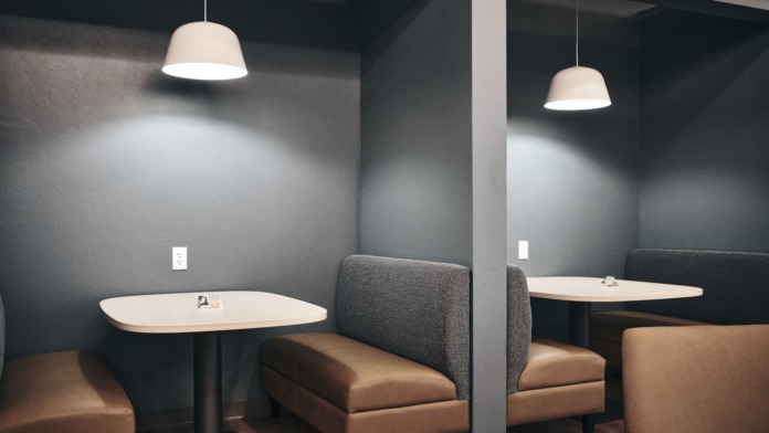 Interior private meeting space featuring individual tables with pendant lighting and upholstered seating dividers