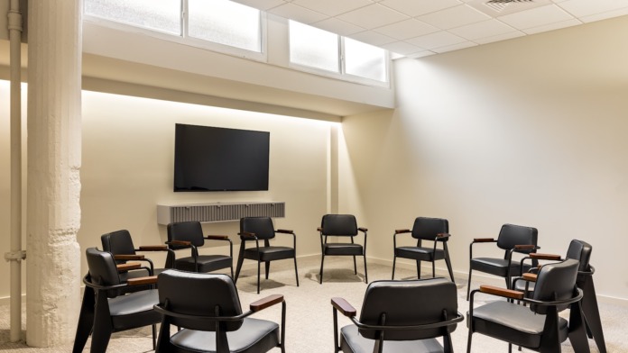 Interior quiet space with comfortable seating chair, table lamp, large window with natural light and privacy screen