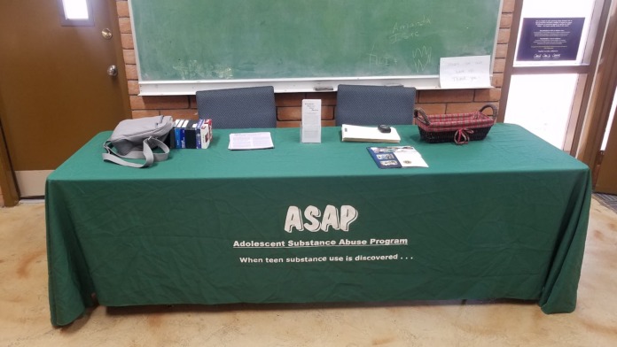 Interior table setup with green tablecloth displaying ASAP program materials and educational resources