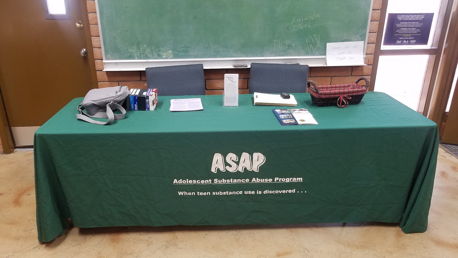 Interior table setup with green tablecloth displaying ASAP program materials and educational resources