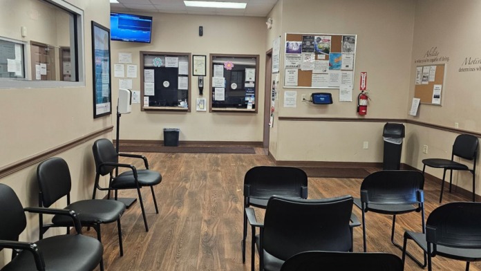 Interior reception waiting area with chairs, wall signage, clock, and office information displays