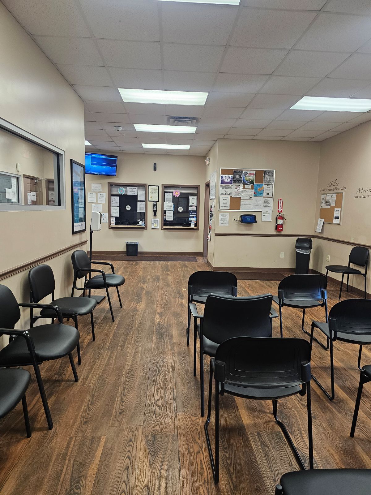 Interior reception waiting area with chairs, wall signage, clock, and office information displays