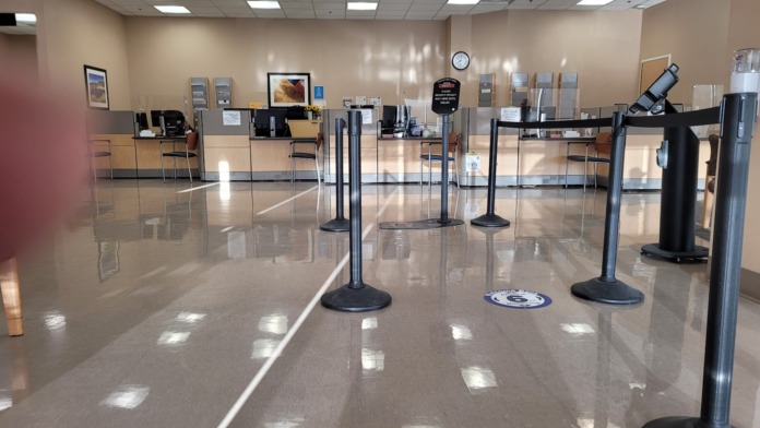 Interior reception area with polished concrete flooring, glass partition barriers, black stanchions, and service desk