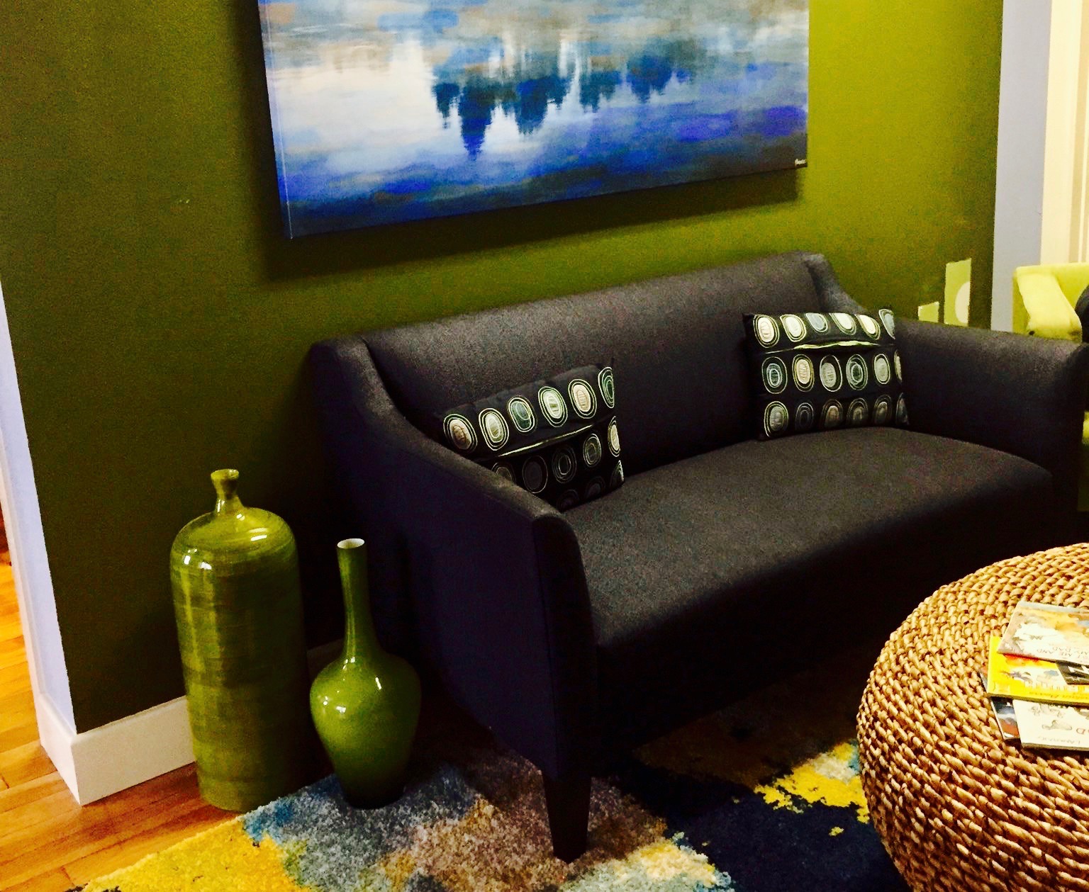 Interior living room with modern black sofa, accent walls, decorative vases, and framed landscape artwork