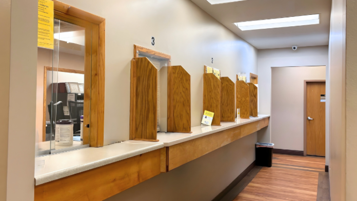 Interior reception area with elevated counter desk, numbered room indicators, mirrors, wooden finish, and open floor plan with multiple access doors