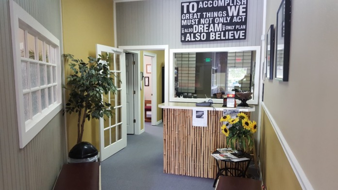 Interior reception space with front desk, yellow walls, decorative artwork, and seating area for clients