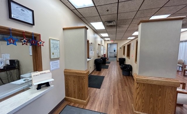 Interior reception hallway with desk counter, beige walls, wood trim, and multiple interior doorways.