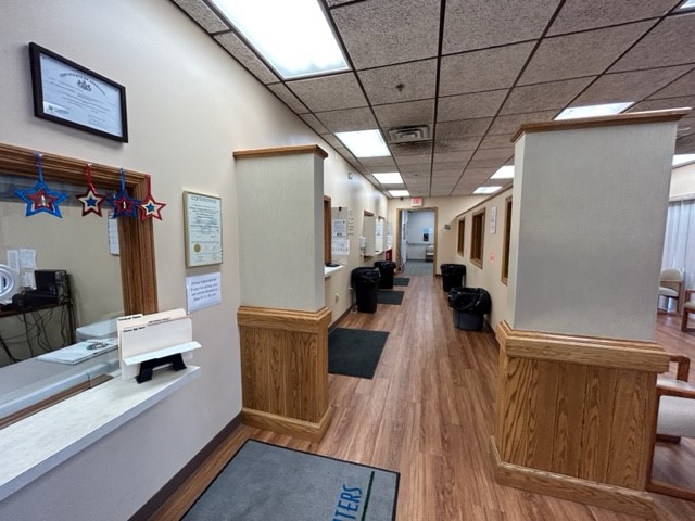 Interior reception hallway with desk counter, beige walls, wood trim, and multiple interior doorways.