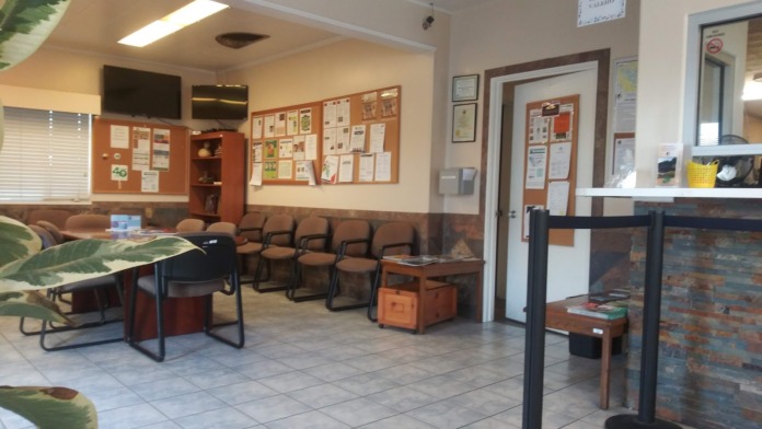 Interior waiting room with tiled floors, upholstered seating, information bulletin boards, and service counter