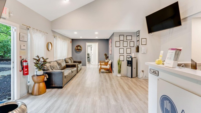 Interior reception space with modern furnishings, comfortable seating, wooden flooring, wall-mounted TV, and reception desk