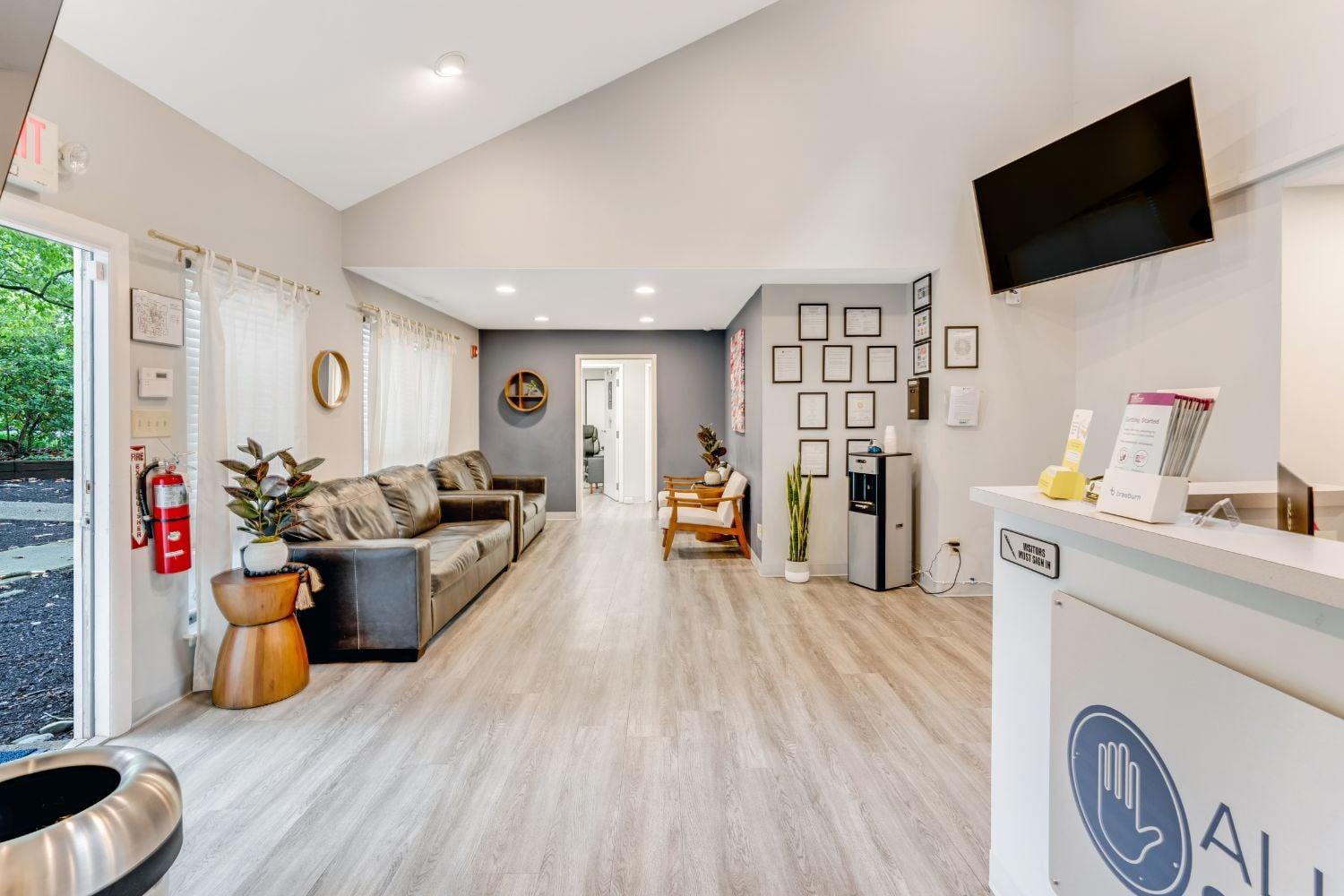 Interior reception space with modern furnishings, comfortable seating, wooden flooring, wall-mounted TV, and reception desk