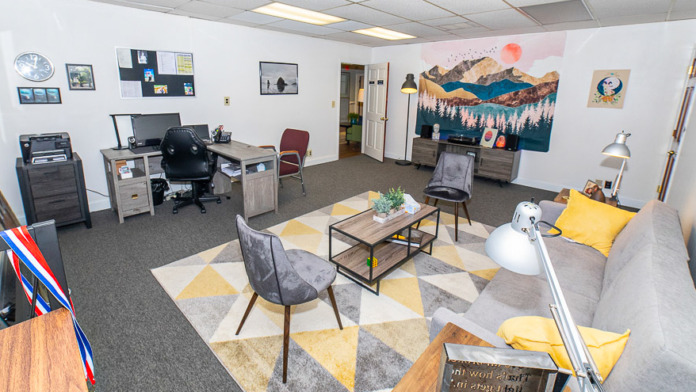 Interior multipurpose room with desk workspace, artwork, seating areas, and storage displaying facility amenities for recreation and activities