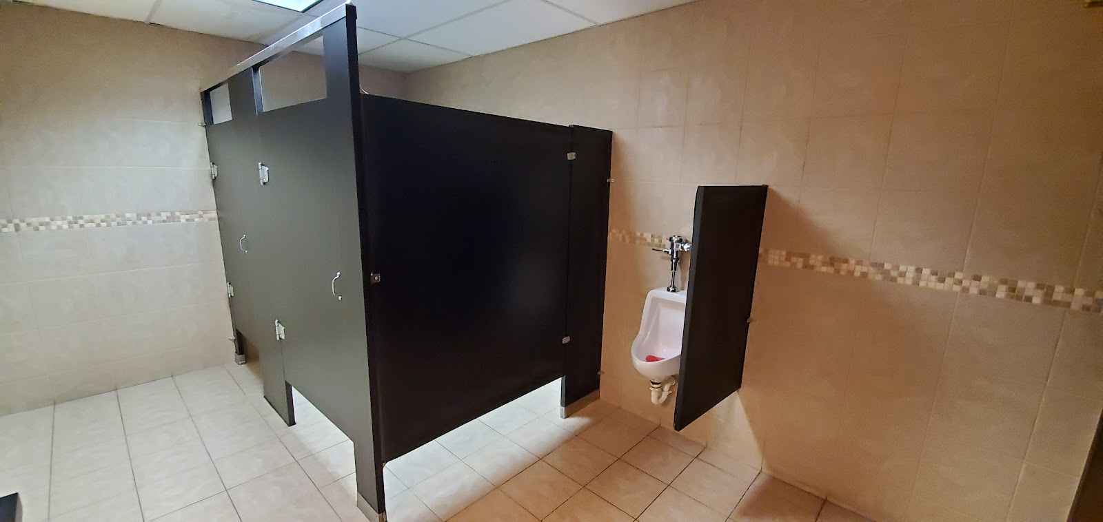 Interior bathroom showing multiple stall compartments with privacy doors and wall-mounted fixtures and dispensers