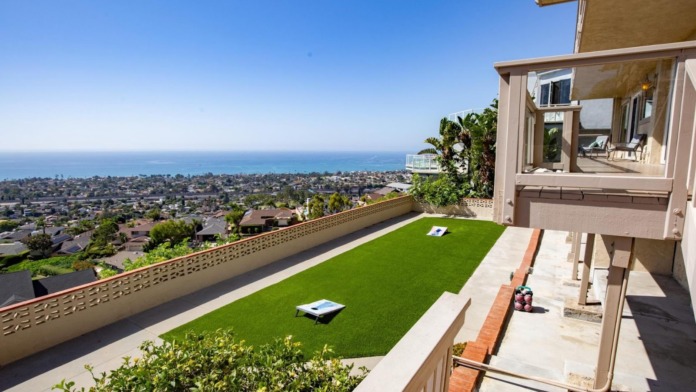 Outdoor rooftop terrace with artificial turf, lounge seating, ocean and coastal landscape views