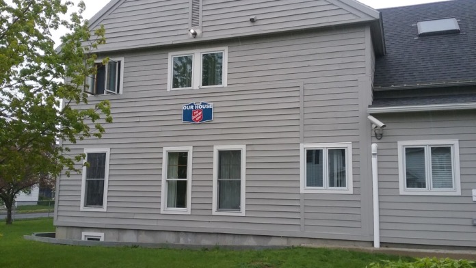 Exterior view of gray two-story residential building with white-trimmed windows and Salvation Army signage