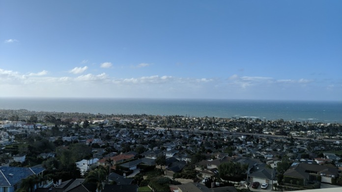 Outdoor balcony view overlooking residential neighborhood, ocean, and coastal landscape