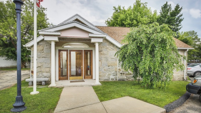 Exterior entrance pavilion with white columns, natural stone construction, and modern glass doors