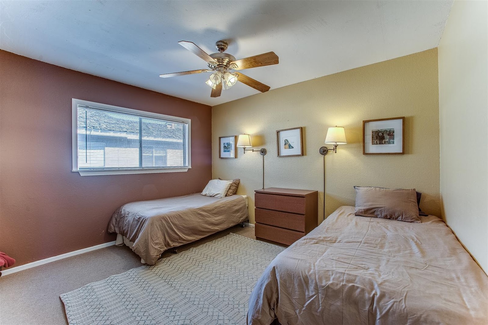 Interior patient bedroom with two twin beds, nightstands, ceiling fan, large window with natural light, and comfortable furnishings