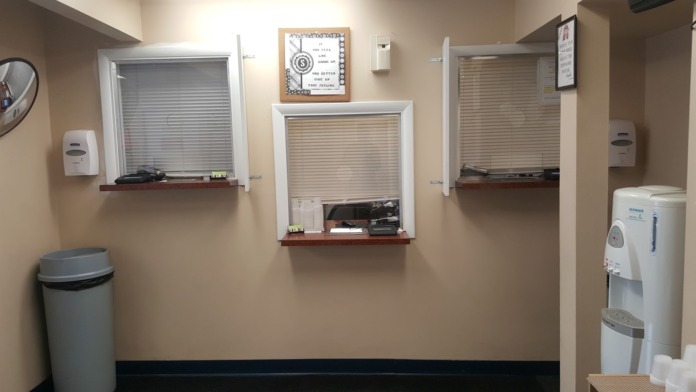 Interior break room with trash bin, windows with blinds, wall-mounted dispenser, water cooler, and informational boards on walls.