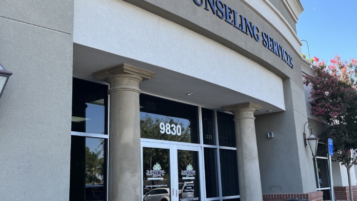 Exterior storefront entrance showing aspire Counseling Services name on facade with glass doors and columns