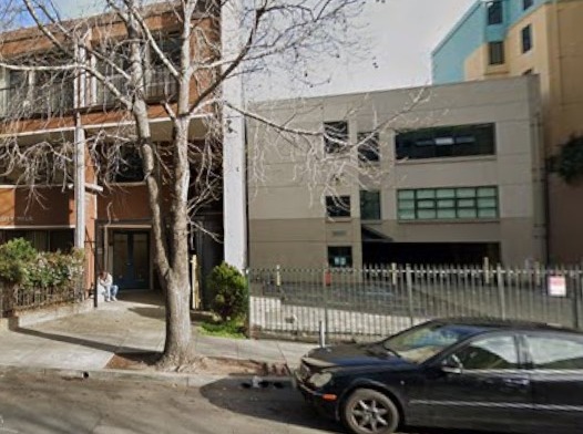 Exterior view of treatment facility building on Addison Street showing multi-story facade, ground floor entrance with green windows, and white perimeter fencing.