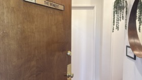 Interior hallway showing Suite 101 entrance door with The Moment Health signage, hanging plants, and wood flooring