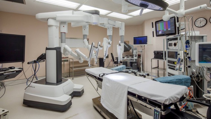 Interior operating room with surgical lights, equipment, examination tables, and medical monitoring systems