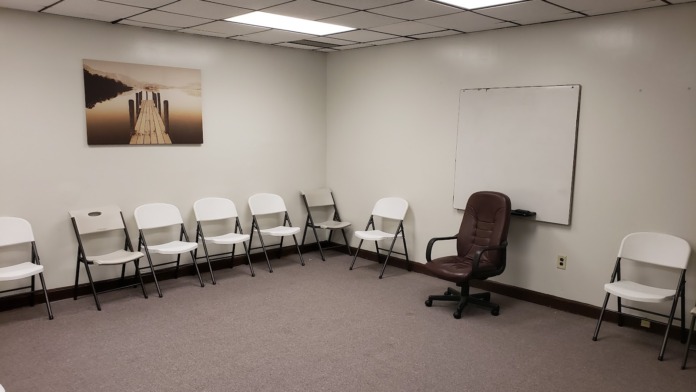 Interior room with semicircular chair arrangement, office chair, whiteboard, landscape wall art, and drop ceiling lighting