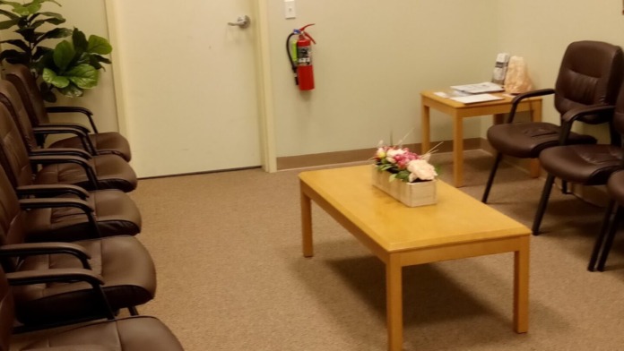 Interior waiting room with comfortable seating, television, plants, and modern furnishings in facility lobby