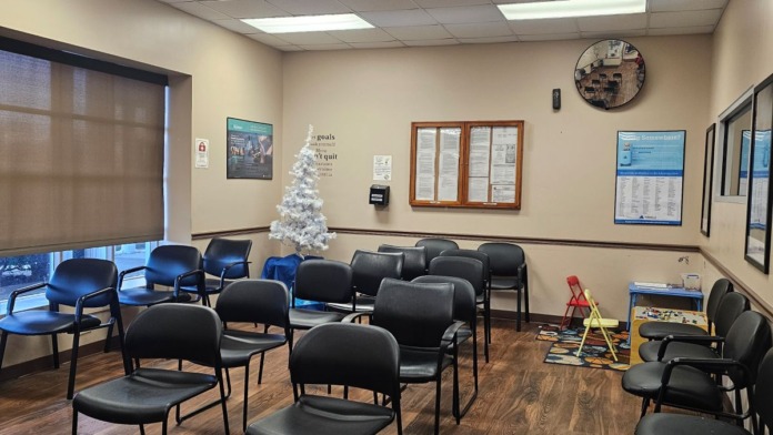 Interior waiting room with multiple black chairs, cream walls, and informational wall displays